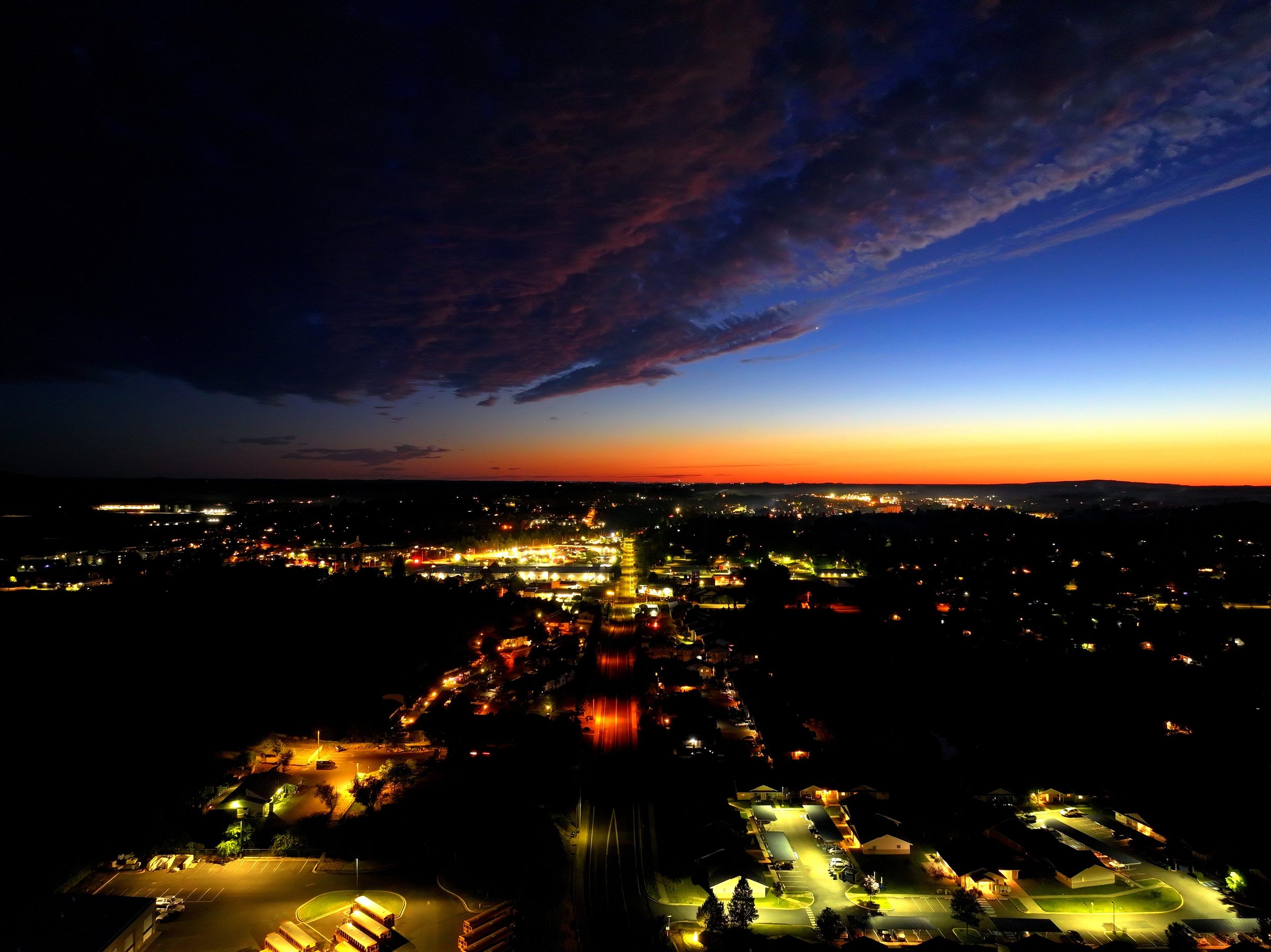 Aerial view of Moscow, Idaho at dusk — town lights beneath an ember horizon